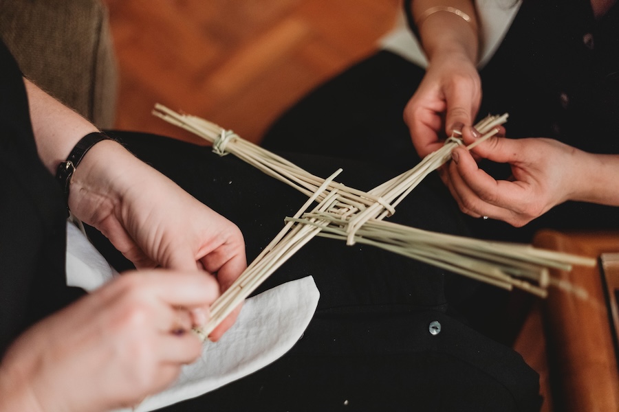 Brigid's Cross being woven by two individuals. Irish-expressions.com.